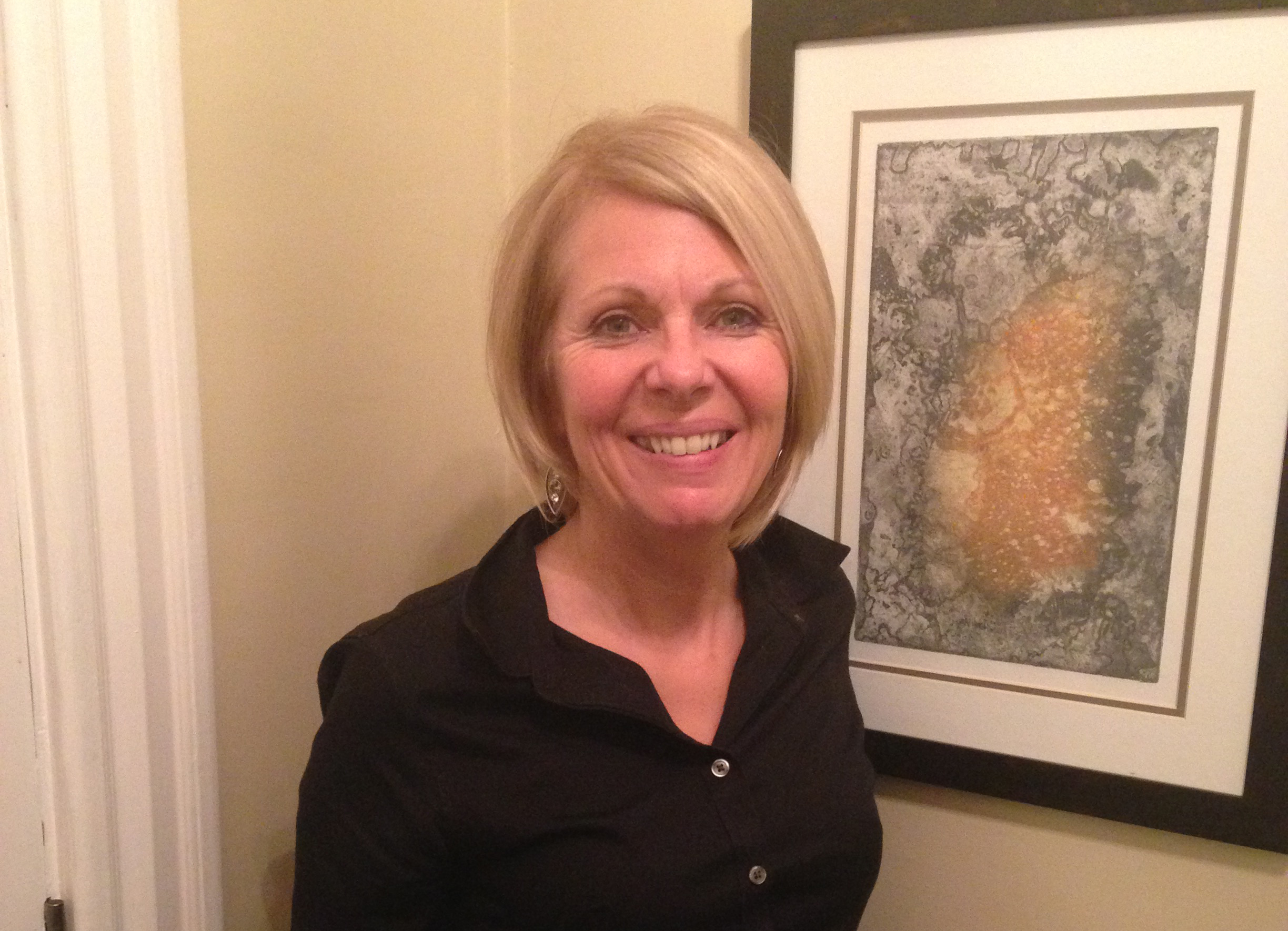 Cheryl McLean head shot smiling in front of a painting