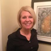 Cheryl McLean head shot smiling in front of a painting
